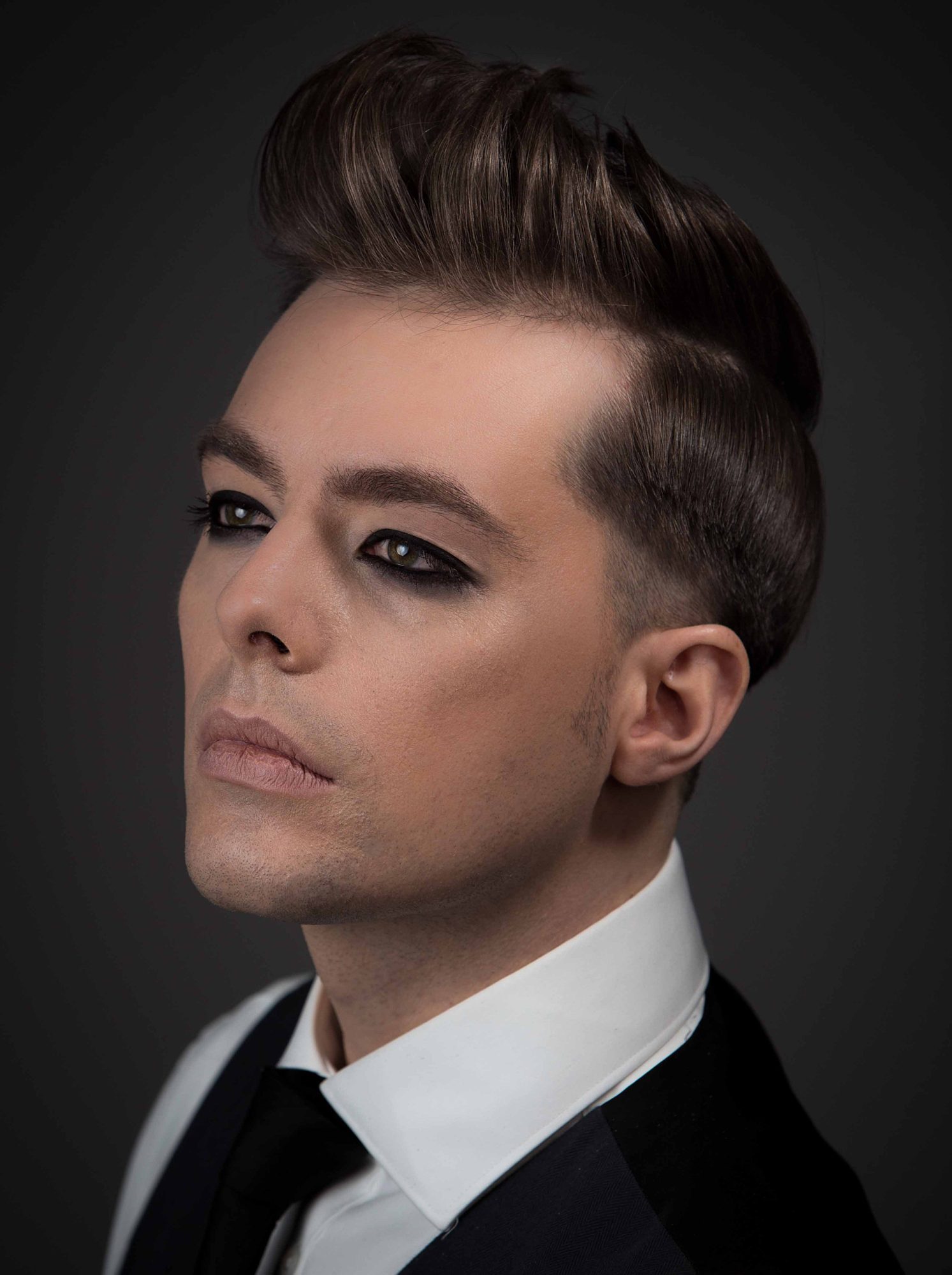 Editorial male portrait in tuxedo with pompadour and dramatic makeup