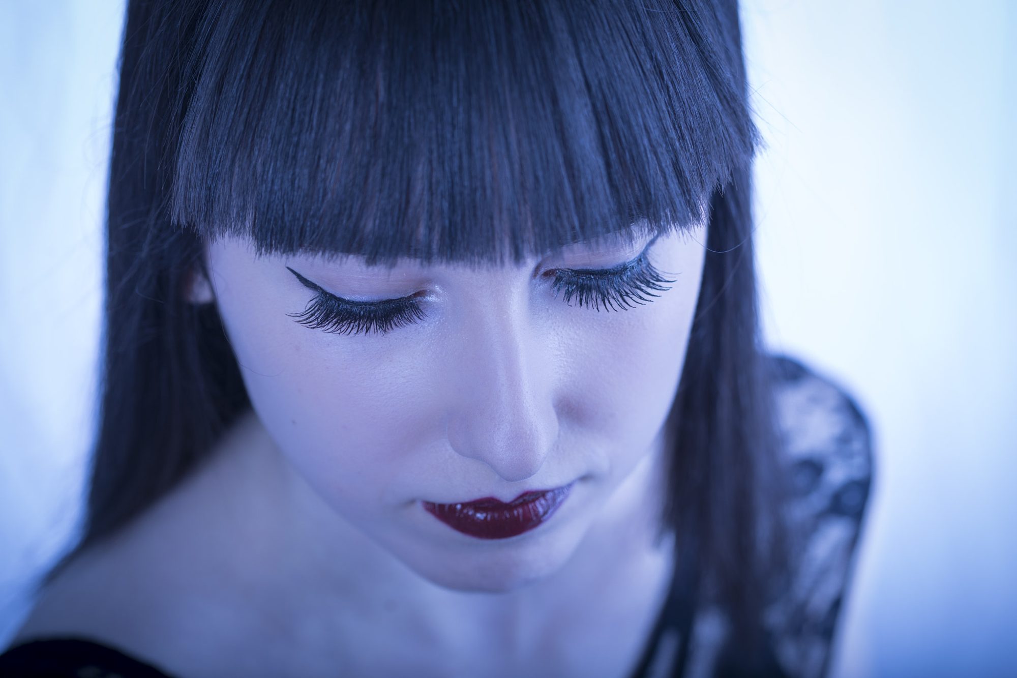 Blue-toned close-up with dramatic lashes