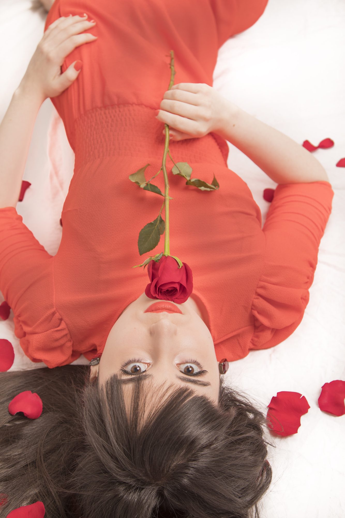 Woman lying down holding a rose in her teeth