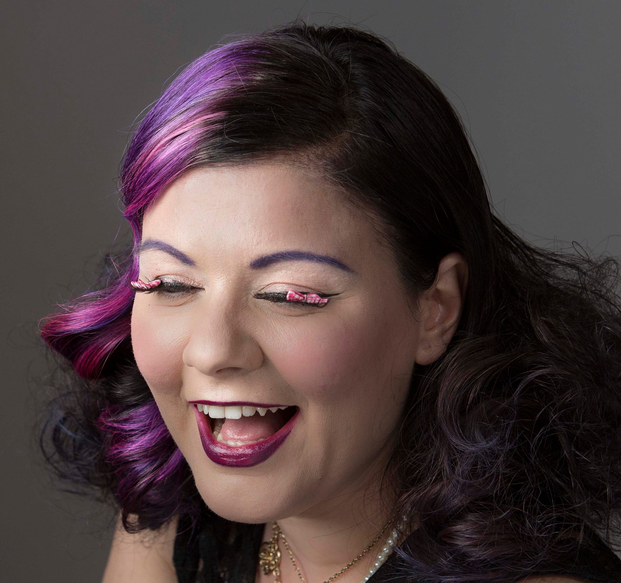Laughing portrait with purple hair and jeweled lashes