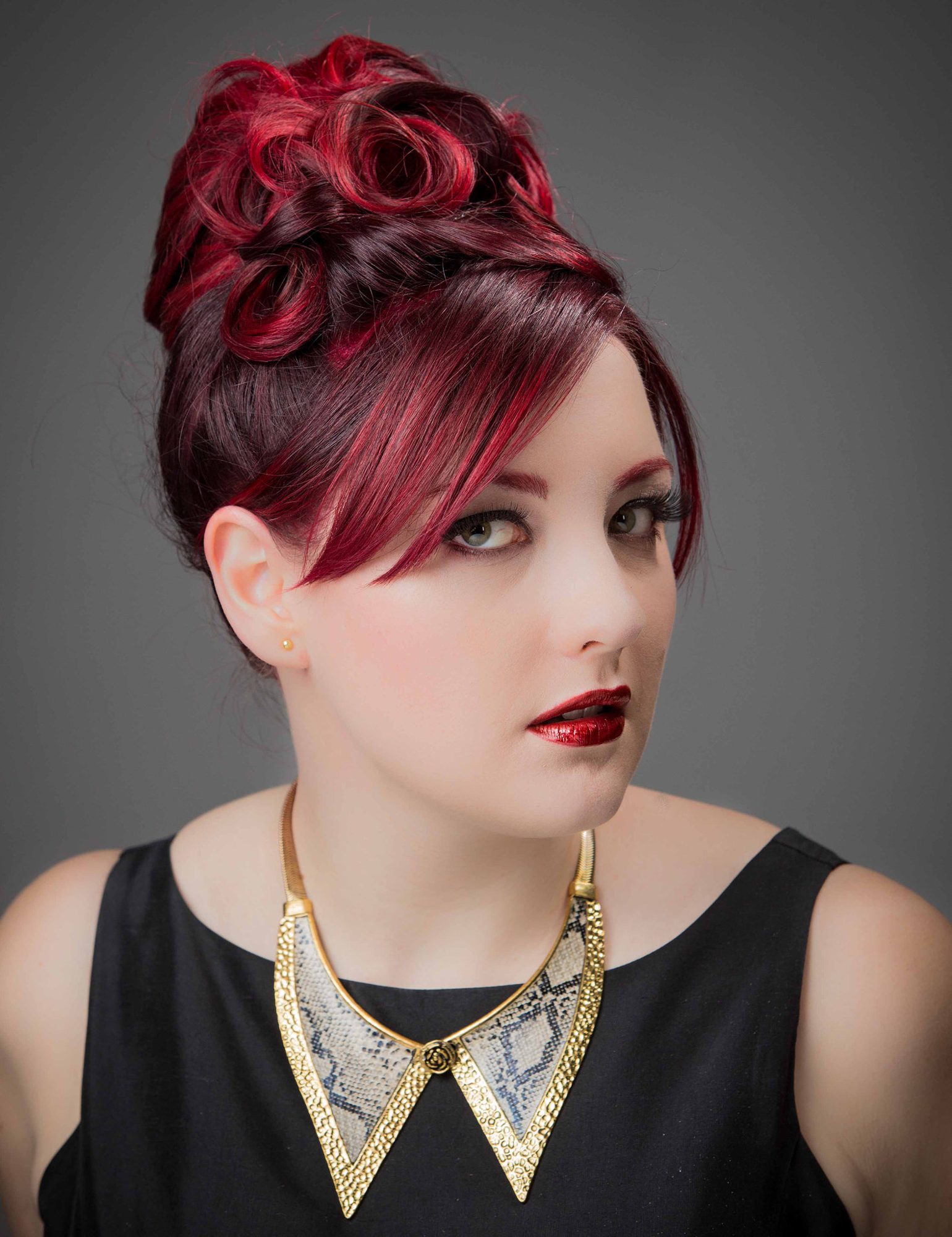 Portrait with red updo and gold collar necklace