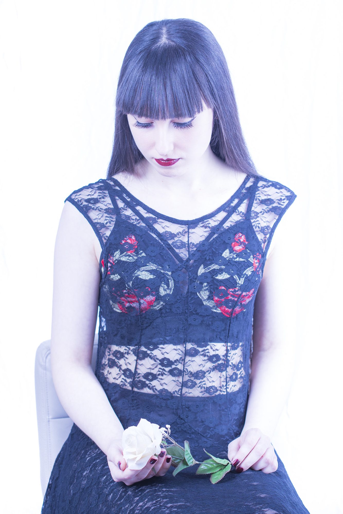 Seated portrait in dark lace holding a white rose